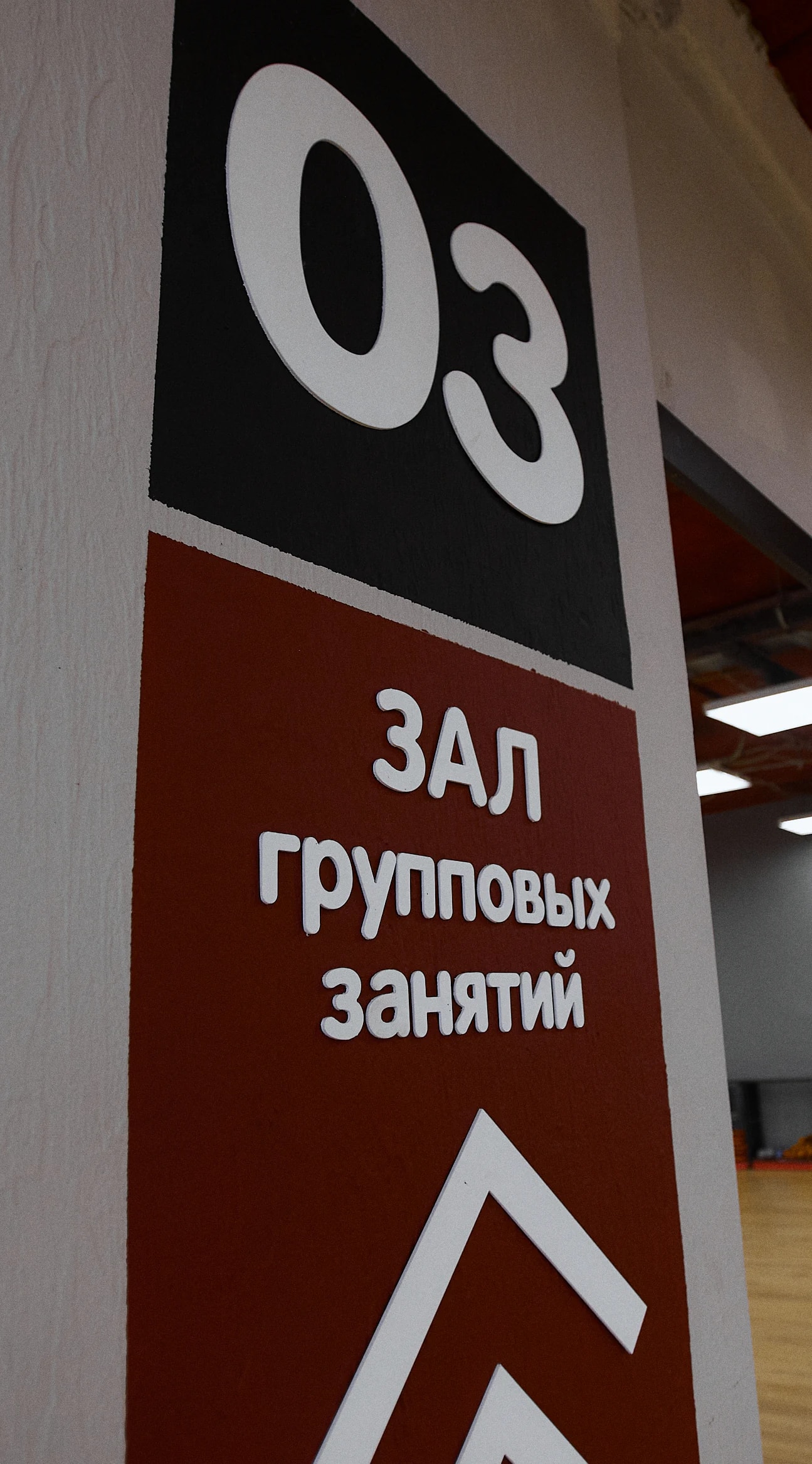 Вход в зал групповых занятий клуба «Станция фитнеса»: указатель на колонне и зеркальная стена
