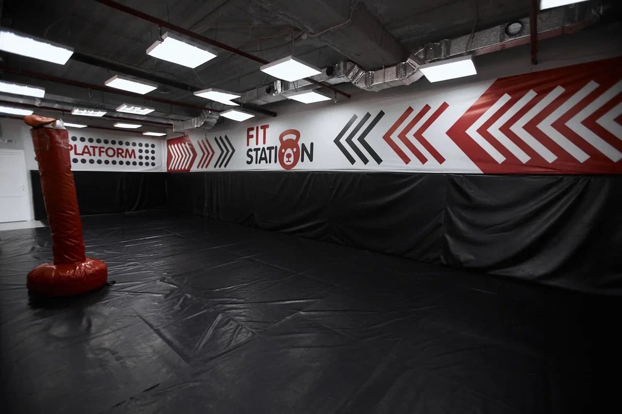 Зал единоборств с матами и надписью FIT STATION на стене